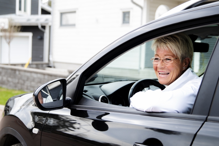 En glad kvinna kör bil i bostadsområde